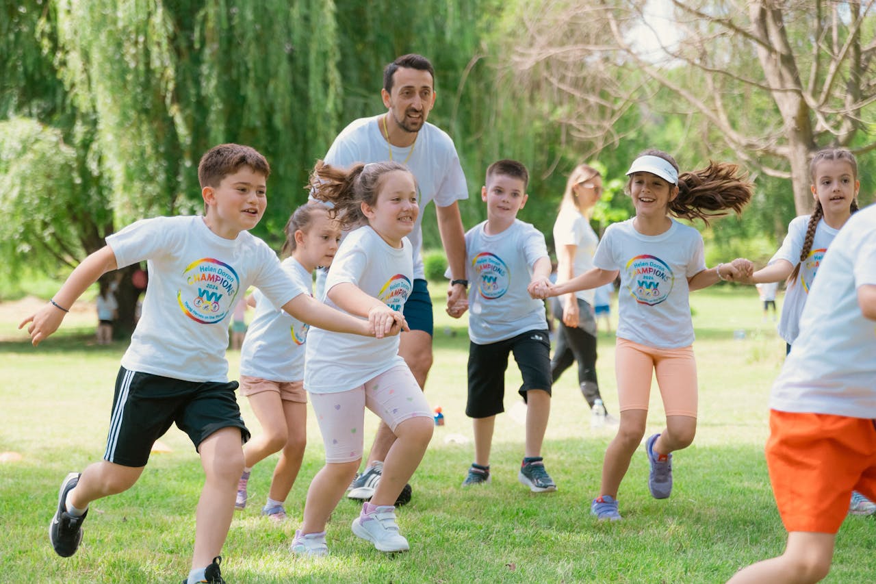 Children joyfully running and holding hands in a sunny park, enjoying outdoor recreation.