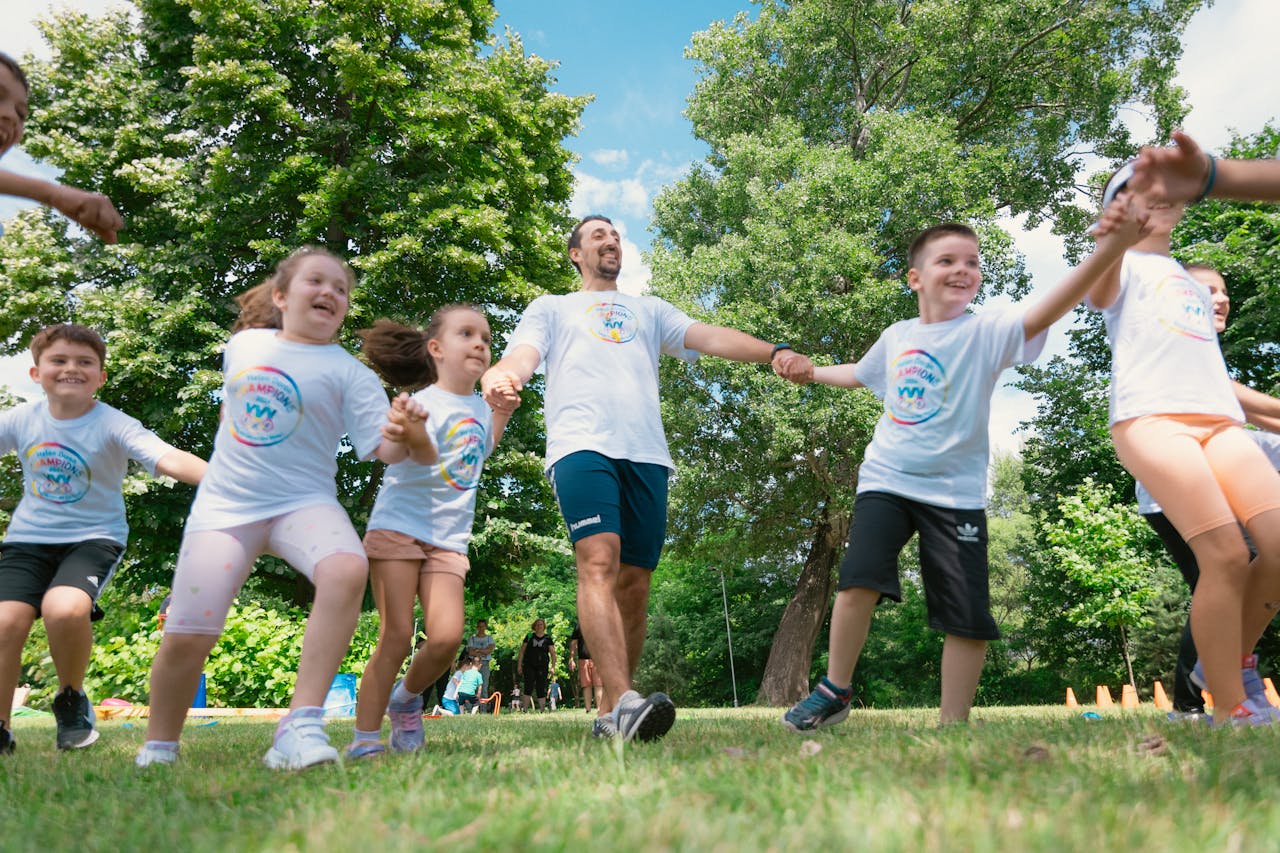 Group of joyful children playing outdoors with an instructor in a sunny park.
